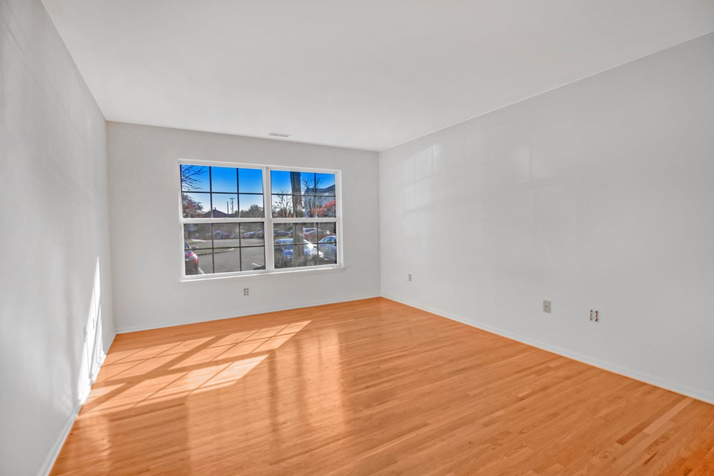 an empty living room with wood floors and a window