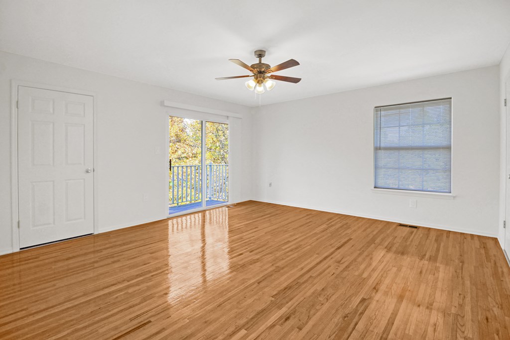 an empty living room with wood floors and a ceiling fan