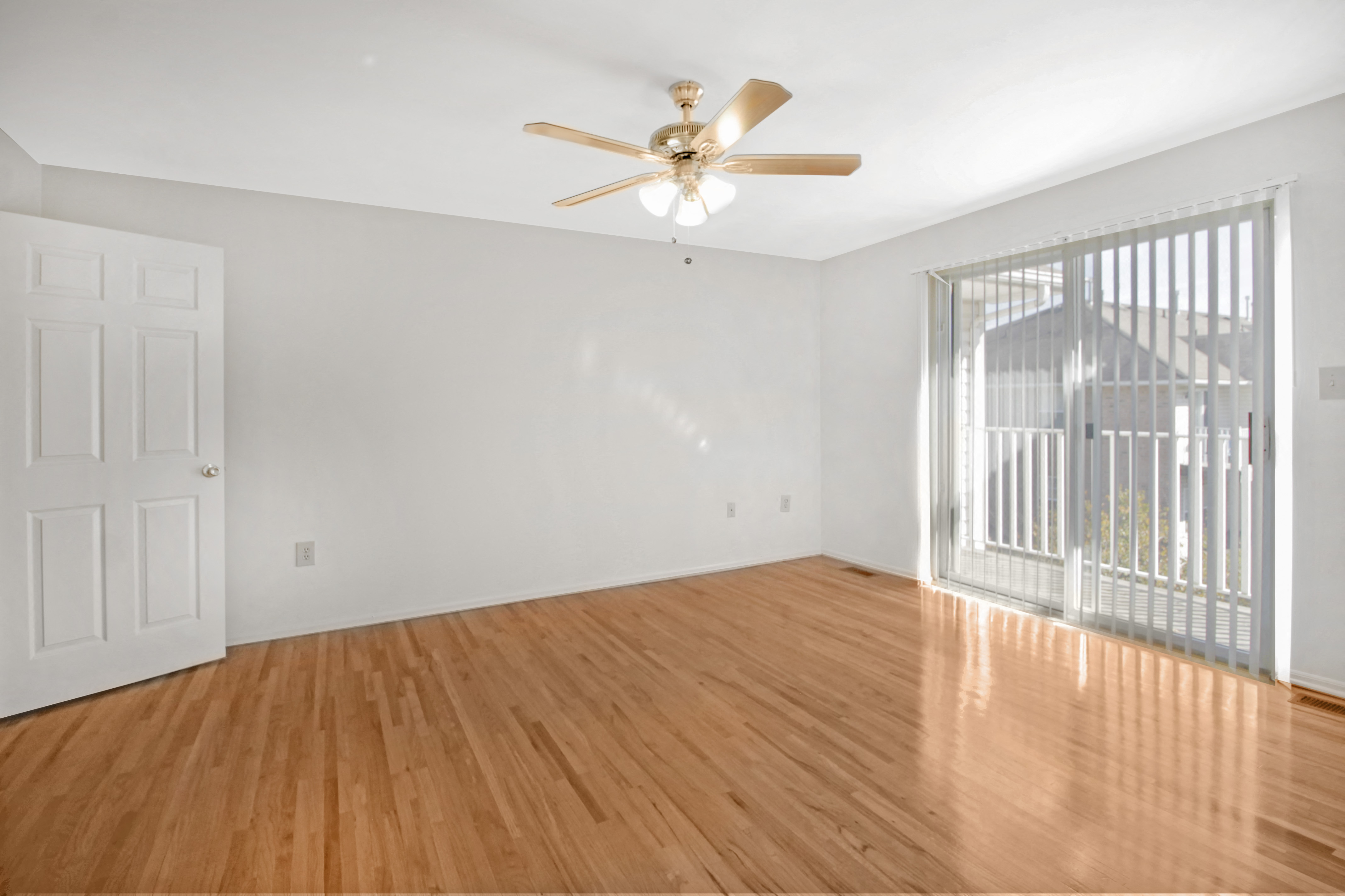 an empty living room with wood floors and a ceiling fan