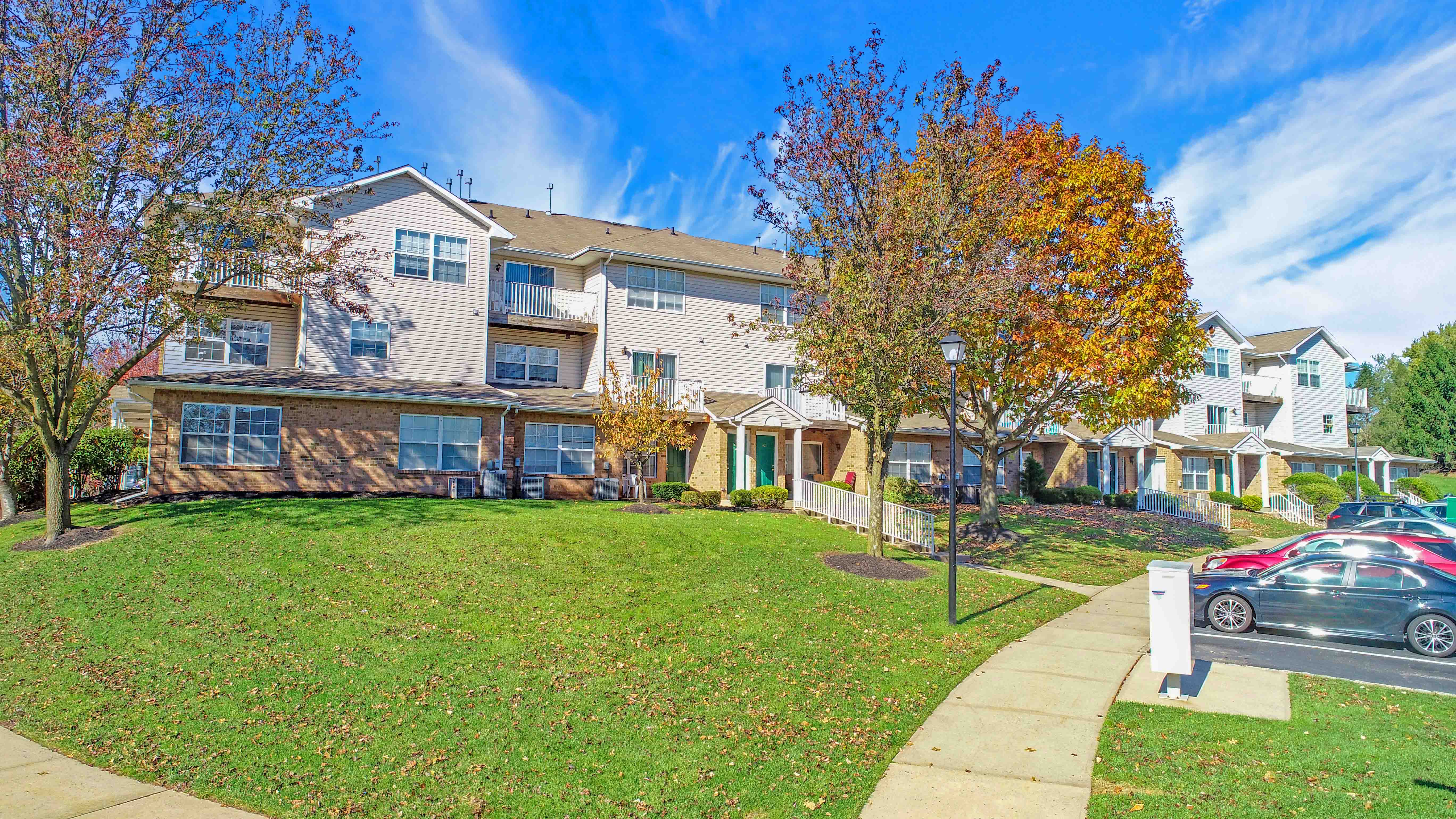 an apartment building with a lawn and cars parked in front of it