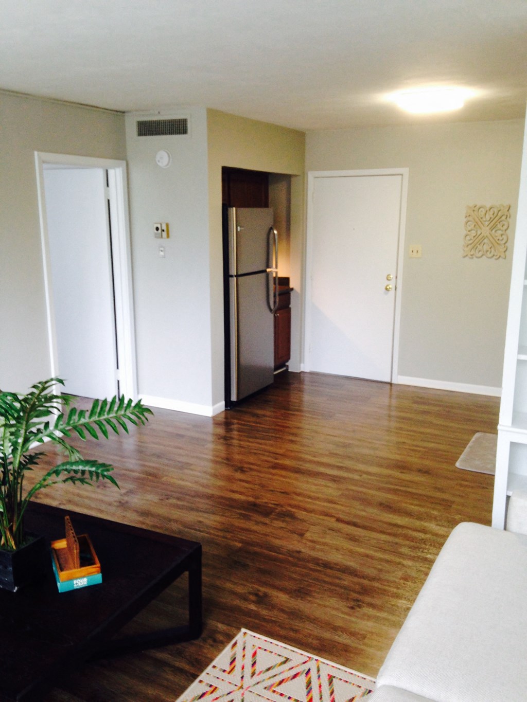 a living room with a hard wood floor and a refrigerator