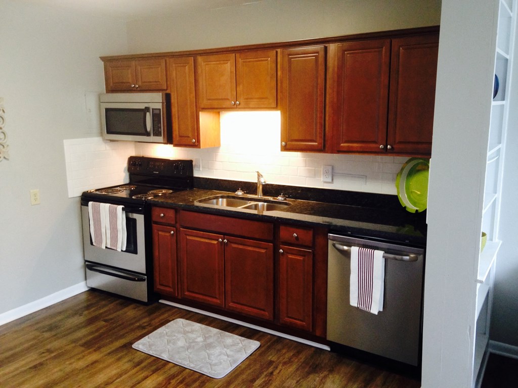 an empty kitchen with wooden cabinets and stainless steel appliances