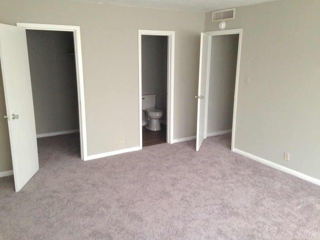 an empty room with three doors and a toilet