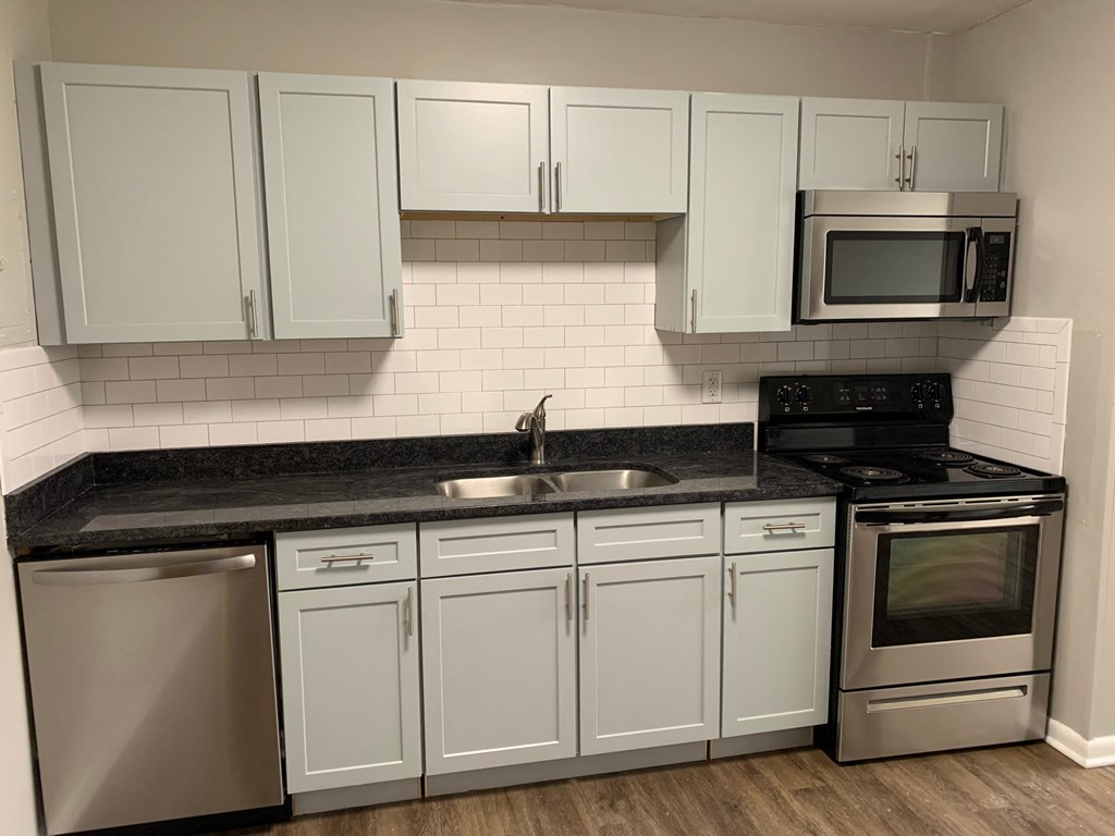 a kitchen with white cabinets and a sink and a stove