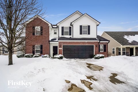 a home in the snow with a black garage door