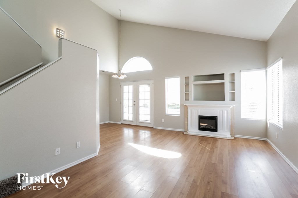 A large empty room with a fireplace and a staircase.