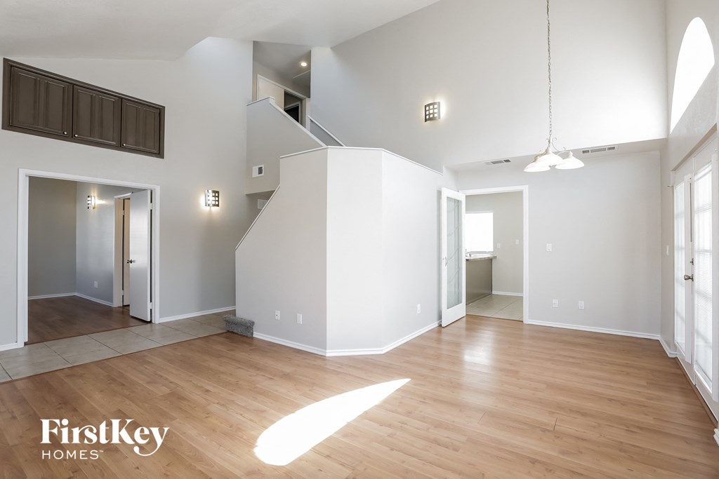 A spacious, empty room with wooden floors and white walls.