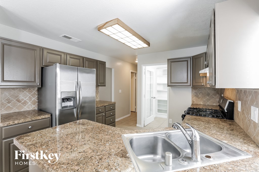 A kitchen with granite countertops and a stainless steel refrigerator.