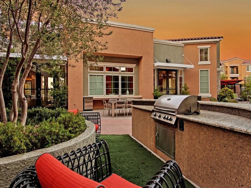 a backyard with a grill and a bar with chairs