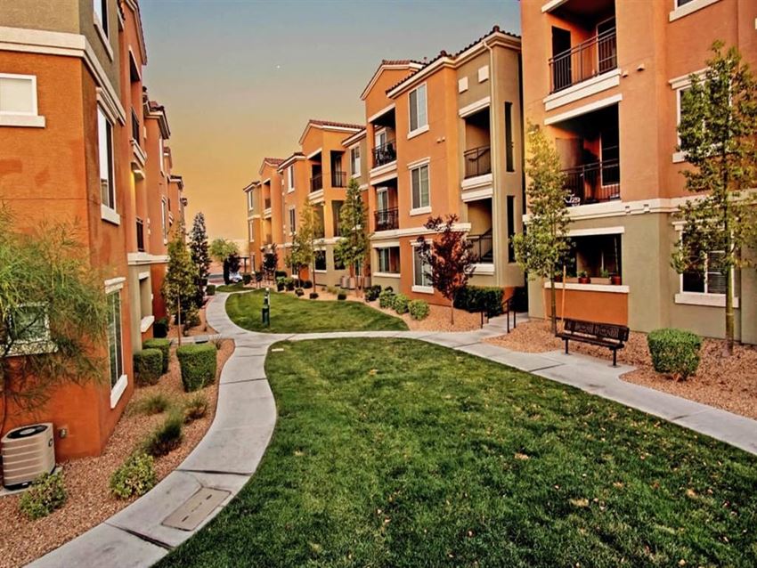 an exterior view of an apartment building with grass and a sidewalk