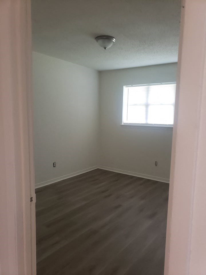 an empty room with wooden floors and a window