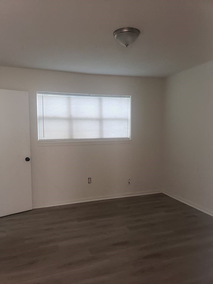 an empty room with a window and wooden floors