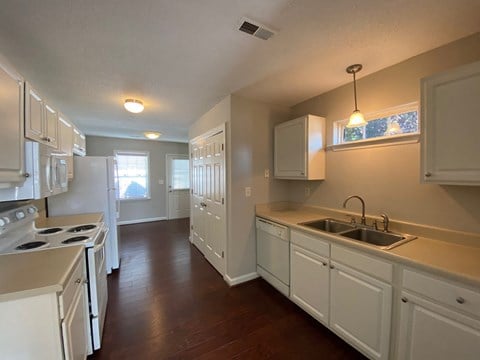 A kitchen with white cabinets and a stove top oven.