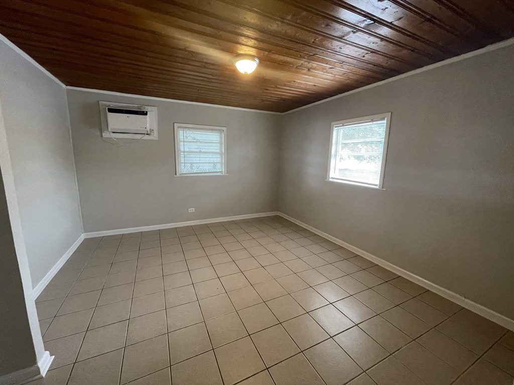 an empty living room with a tiled floor and a wood ceiling