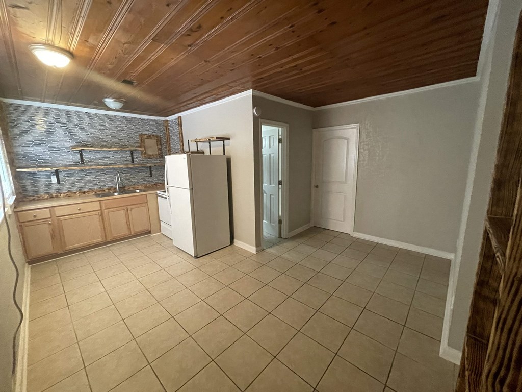 an empty kitchen with a refrigerator and a sink
