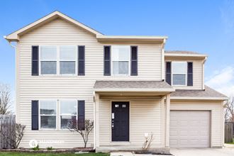 a white house with a black door and two garage doors
