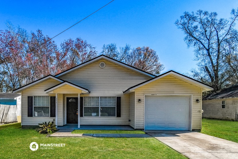 a cream colored house with a white garage door on a lawn