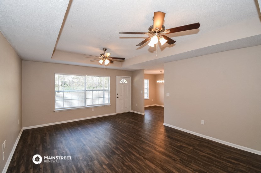 an empty living room with a ceiling fan and a window