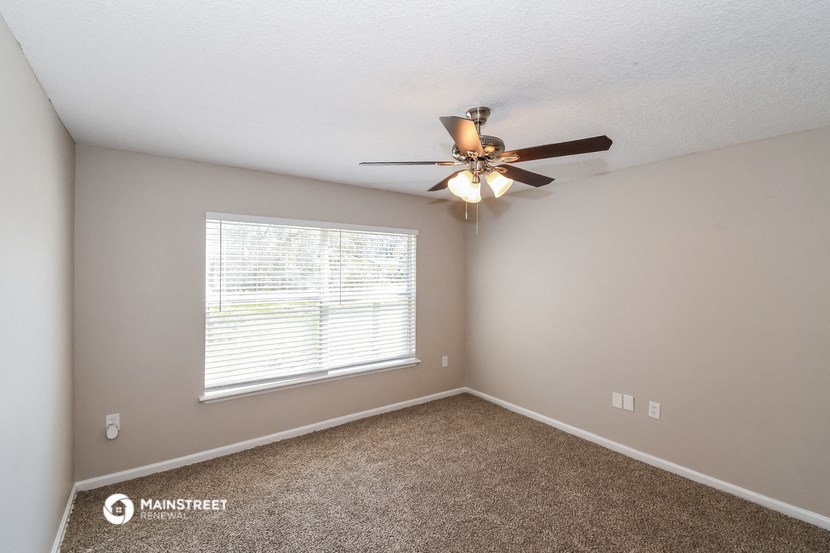 the spacious bedroom has a ceiling fan and a large window