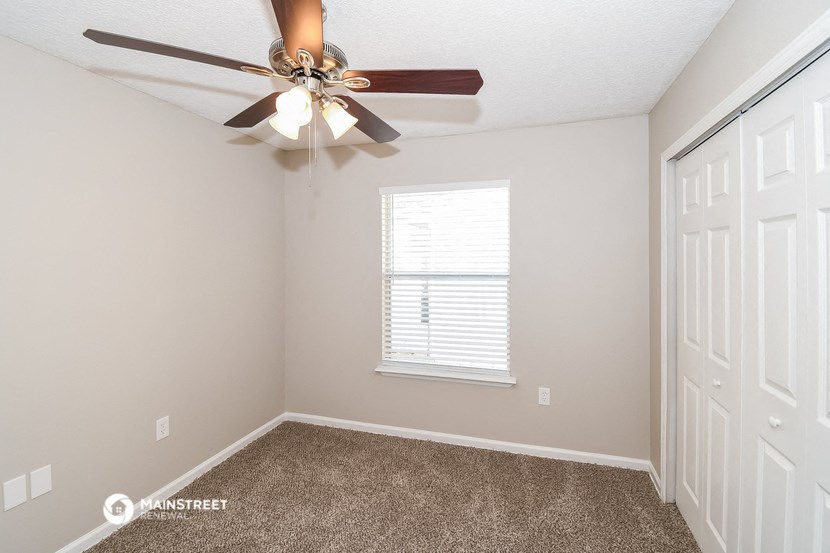 the bedroom has a ceiling fan and a closet