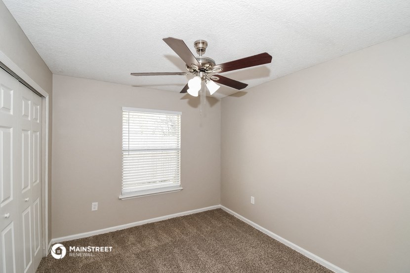 the bedroom has a ceiling fan and a carpet