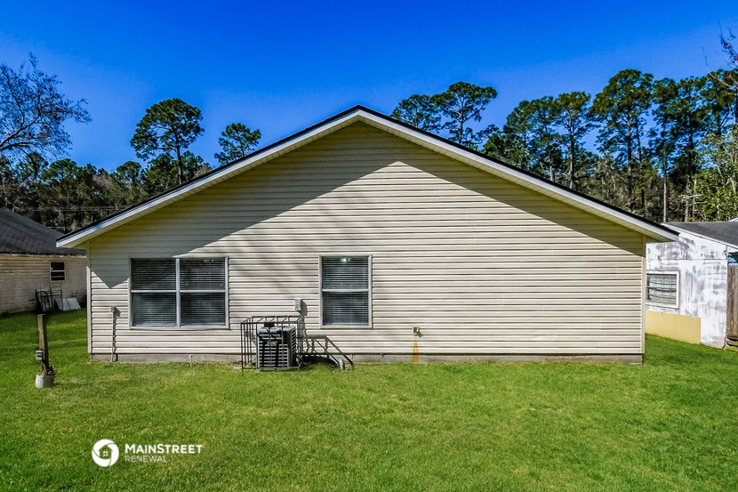the front of a white house with a yard in front of it