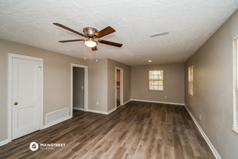 an empty living room with wood flooring and a ceiling fan