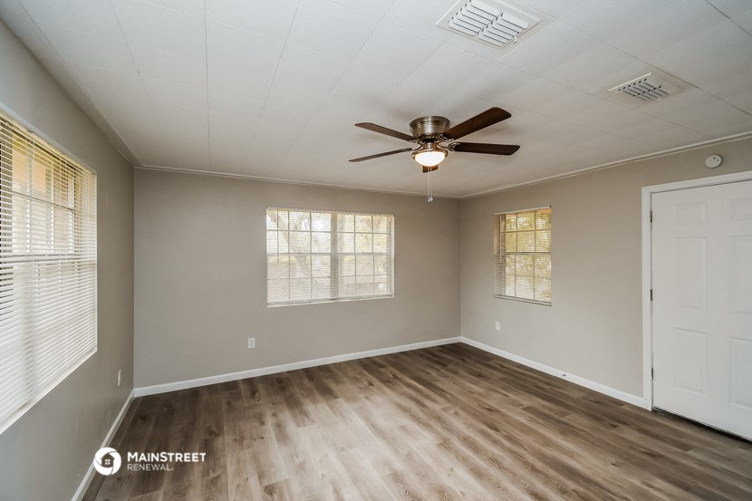the spacious living room with wood flooring and a ceiling fan