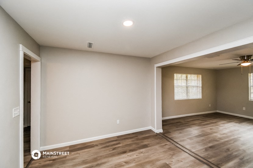 the spacious living room with hardwood floors and a ceiling fan