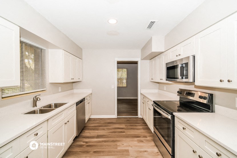 a kitchen with white cabinets and a black stove and a microwave