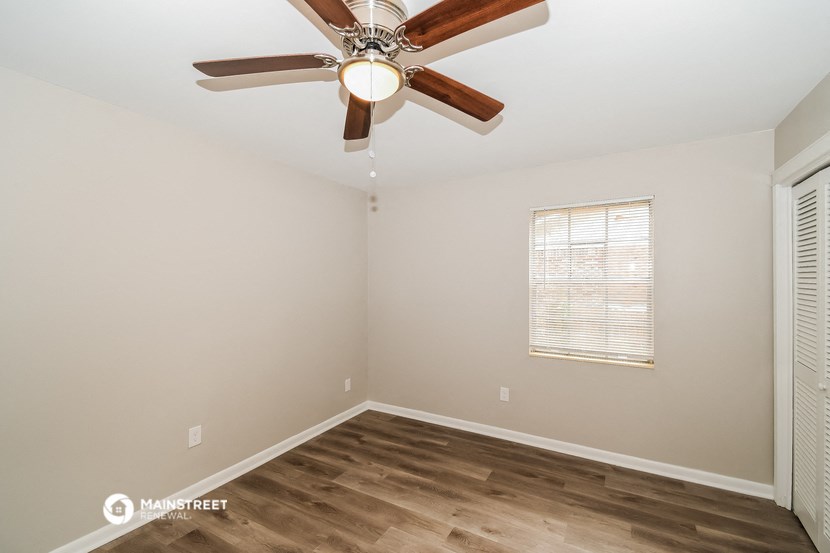 the spacious living room with ceiling fan and wood flooring