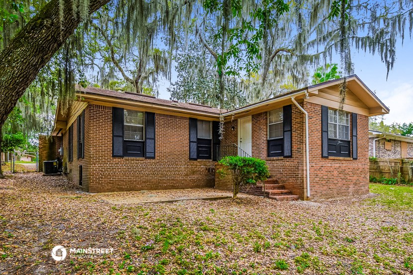 an old brick house with a weeping willow tree