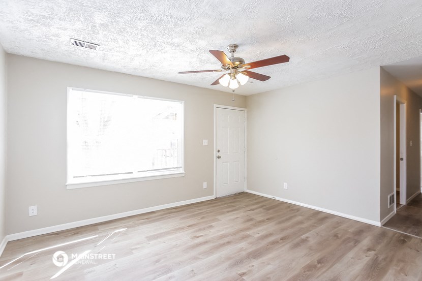 an empty living room with a ceiling fan and a window