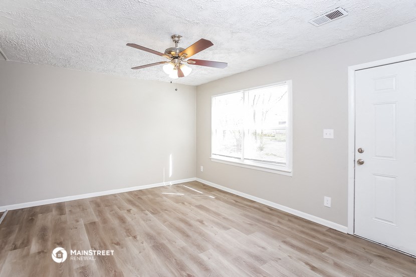 an empty bedroom with a ceiling fan and a window
