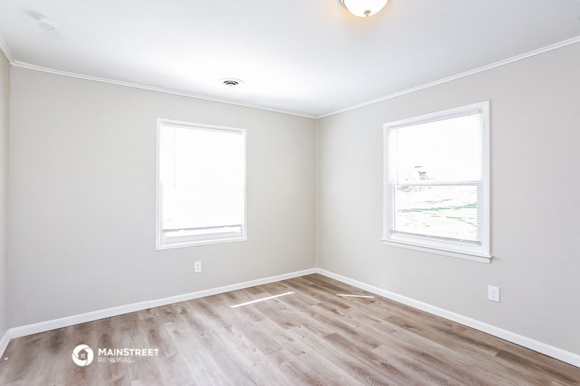 an empty room with a wood floor and two windows