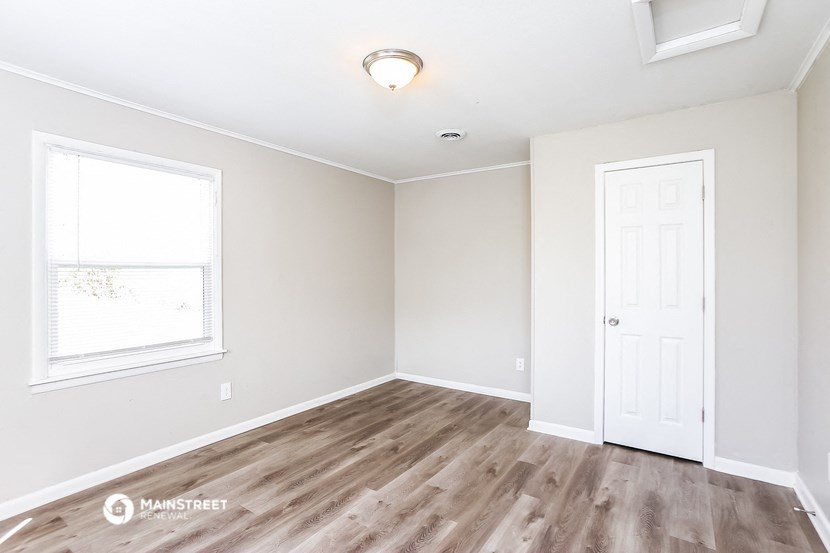 an empty room with a white door and a window