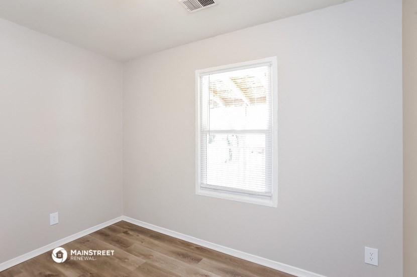 an empty room with a window and a wooden floor