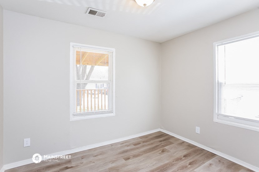 an empty room with a wood floor and two windows