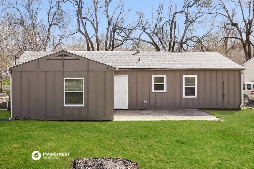 a small brown shed with a white door on the side of a lawn