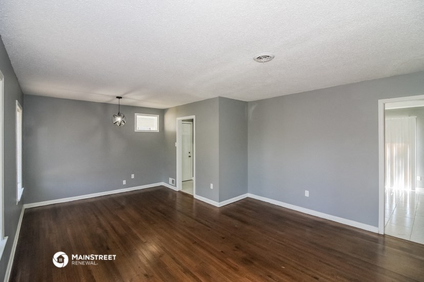an empty living room with wood floors and grey walls