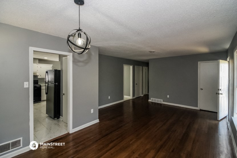 an empty living room with a hard wood floor and grey walls