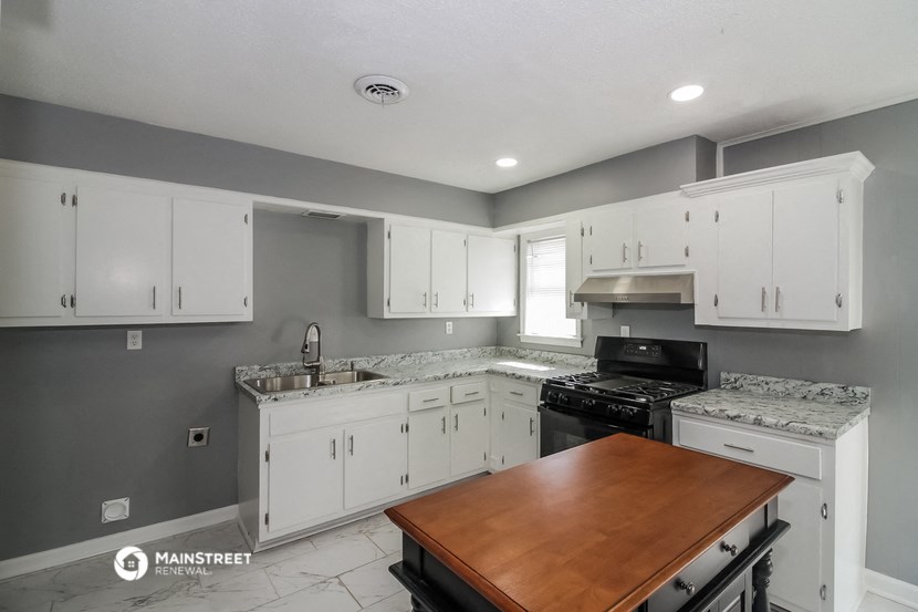 a kitchen with white cabinets and black appliances and a wooden counter top