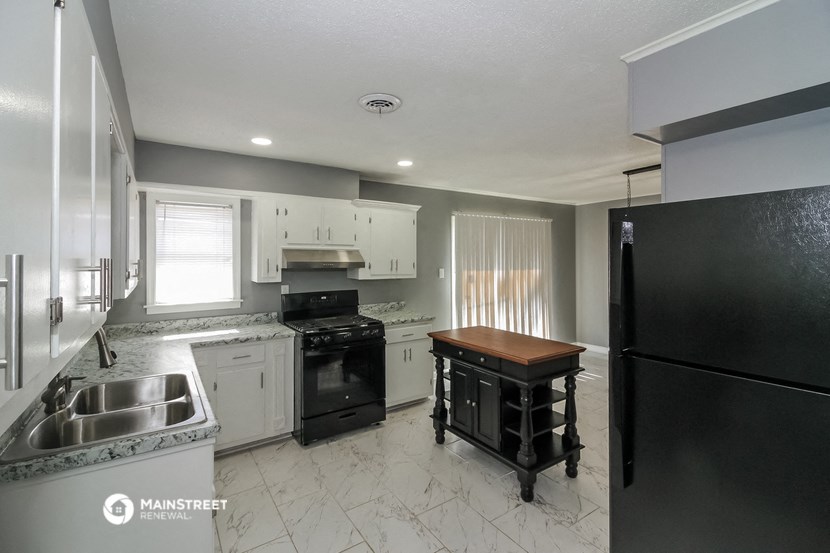 a kitchen with white cabinets and black appliances