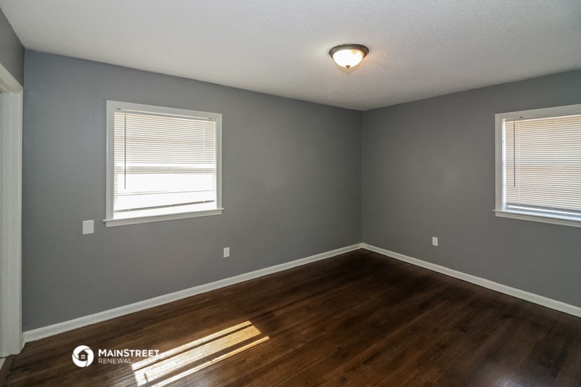 the interior of a house with a wooden floor and two windows