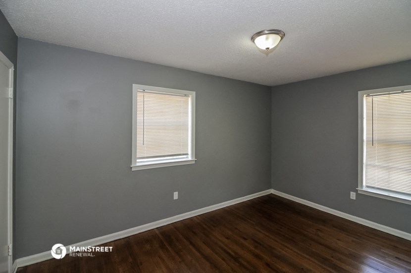 the interior of a house with a hard wood floor and two windows