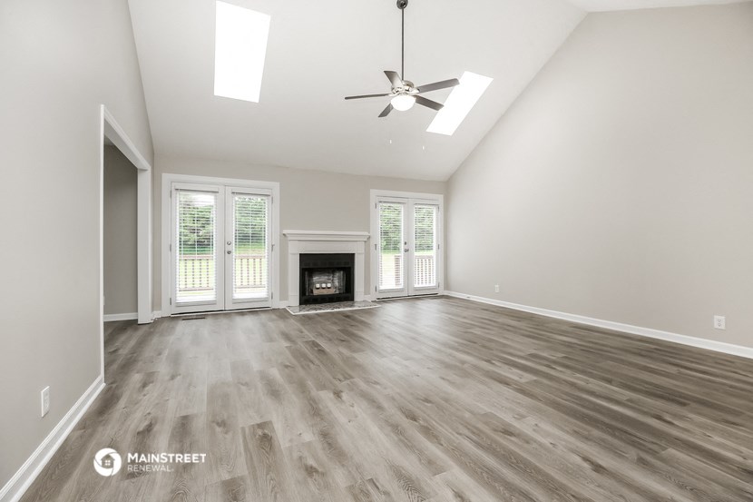 an empty living room with a fireplace and a ceiling fan