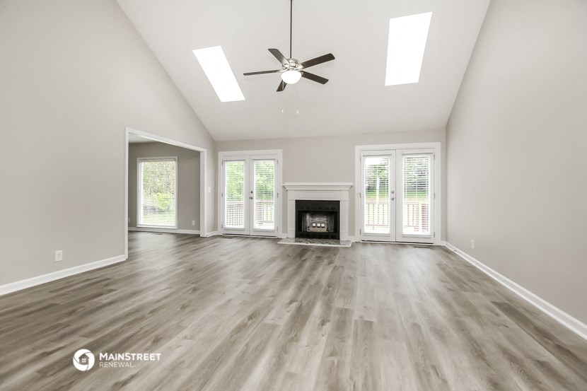 the living room with a fireplace and a ceiling fan