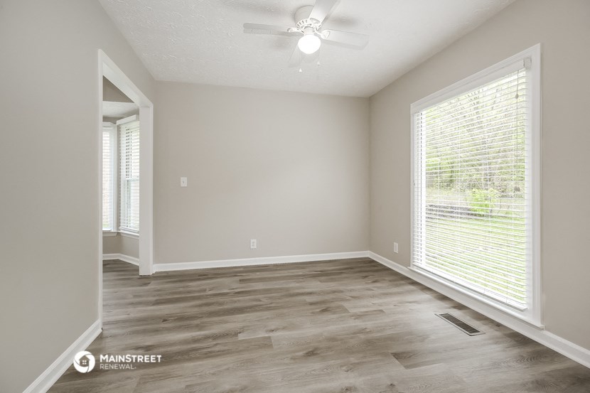 the spacious living room with a large window and wood flooring