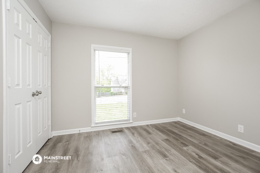 the spacious living room with wood flooring and a window