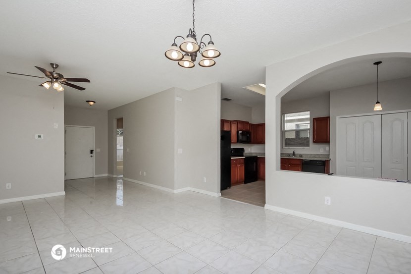 an empty living room and kitchen with a ceiling fan
